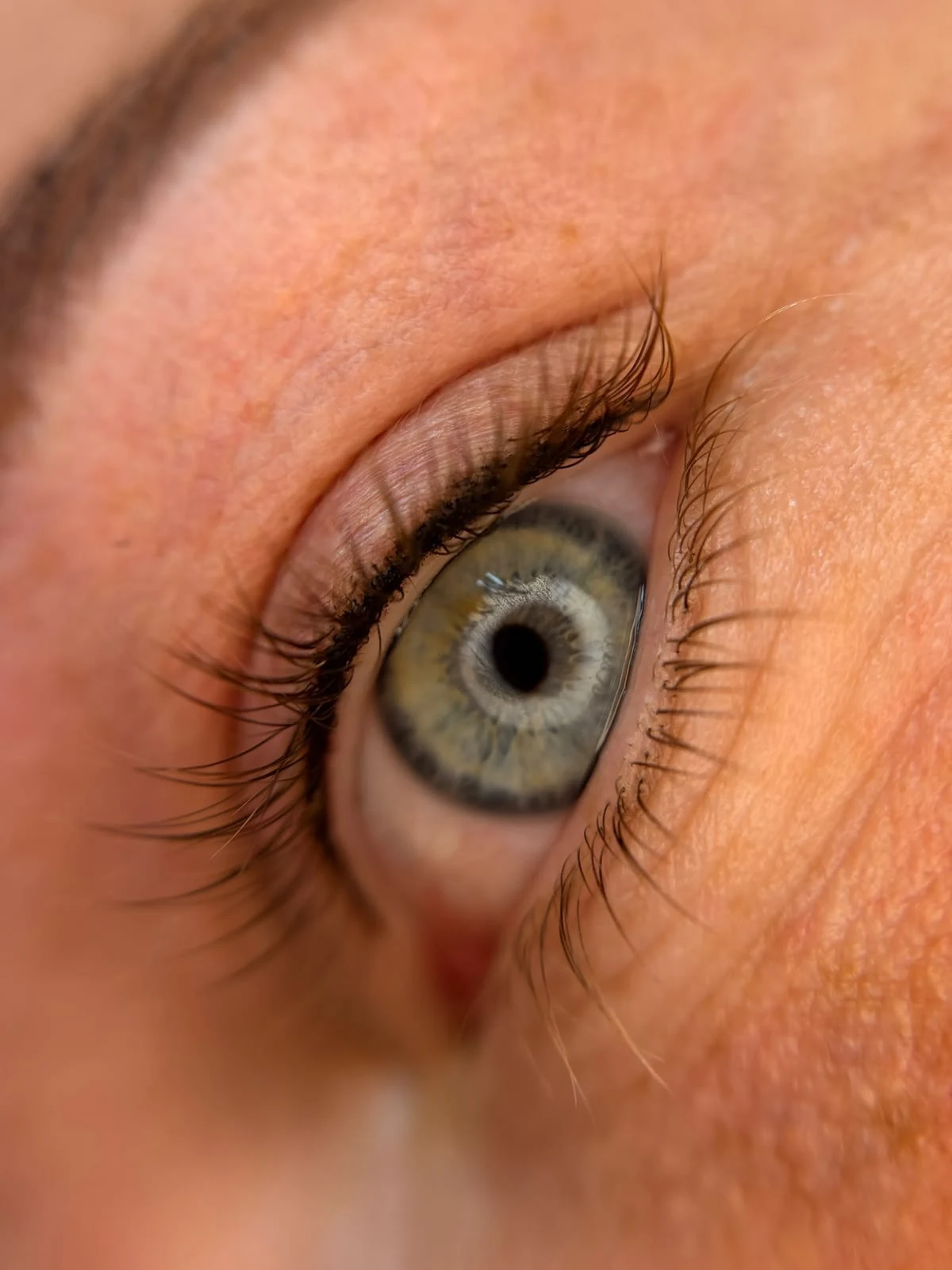 By Shay brengt pigment aan tijdens een PMU-behandeling rond de wimpers